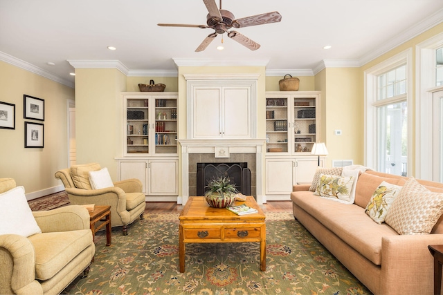 living room featuring a tiled fireplace, crown molding, dark hardwood / wood-style flooring, and ceiling fan