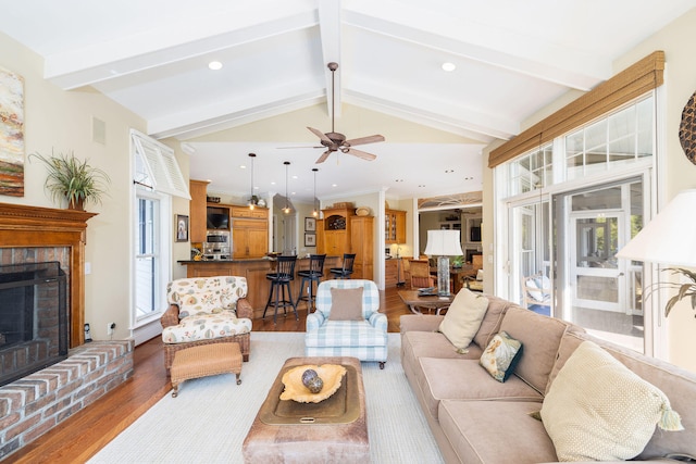 living room with lofted ceiling with beams, a fireplace, wood-type flooring, and ceiling fan