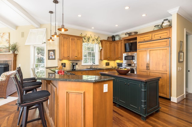 kitchen featuring a kitchen island, dark hardwood / wood-style floors, built in appliances, hanging light fixtures, and sink