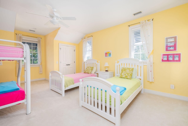 bedroom with a closet, ceiling fan, light carpet, and multiple windows