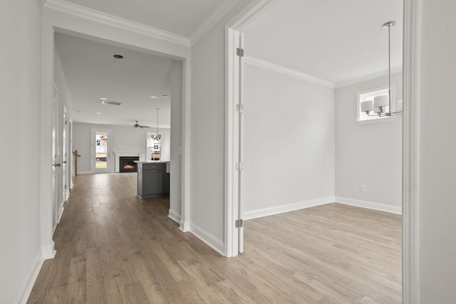 hallway with light wood-type flooring and ornamental molding