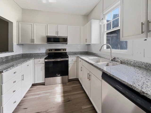 kitchen featuring wood-type flooring, stainless steel appliances, sink, and white cabinetry