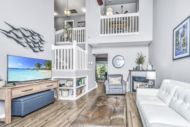 living area with a high ceiling, a fireplace, wood finished floors, visible vents, and baseboards