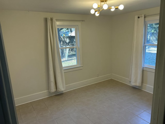 spare room with a wealth of natural light, light tile patterned floors, and a chandelier