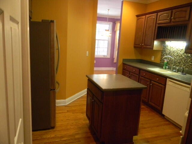 kitchen with a kitchen island, sink, stainless steel refrigerator, light hardwood / wood-style flooring, and white dishwasher