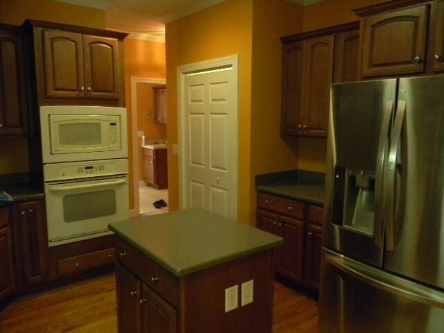 kitchen with a kitchen island, dark hardwood / wood-style flooring, and white appliances