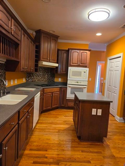 kitchen featuring light hardwood / wood-style floors, white appliances, tasteful backsplash, and a center island