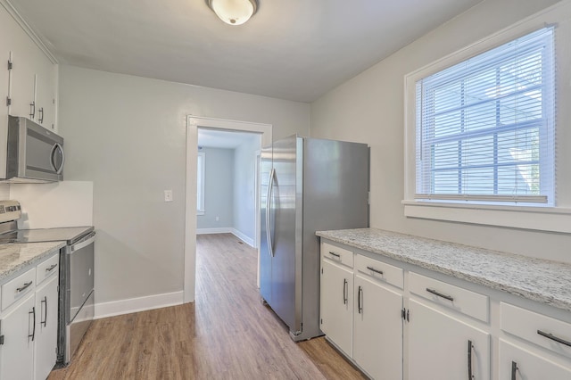 kitchen featuring baseboards, appliances with stainless steel finishes, light wood-type flooring, and white cabinets