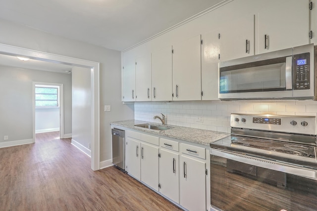 kitchen featuring stainless steel appliances, decorative backsplash, white cabinets, a sink, and wood finished floors