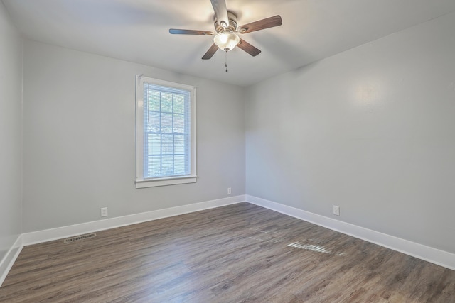 spare room featuring visible vents, ceiling fan, baseboards, and wood finished floors