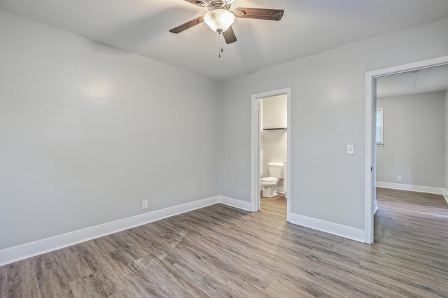 unfurnished bedroom with ensuite bathroom, wood finished floors, attic access, and baseboards