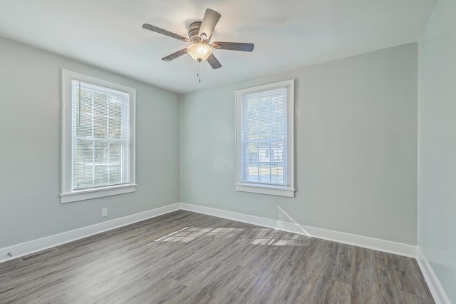 spare room with a ceiling fan, wood finished floors, visible vents, and baseboards