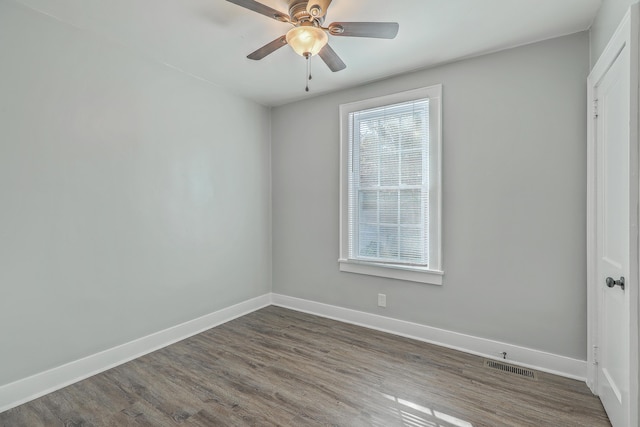 unfurnished room featuring a ceiling fan, baseboards, visible vents, and dark wood-style flooring