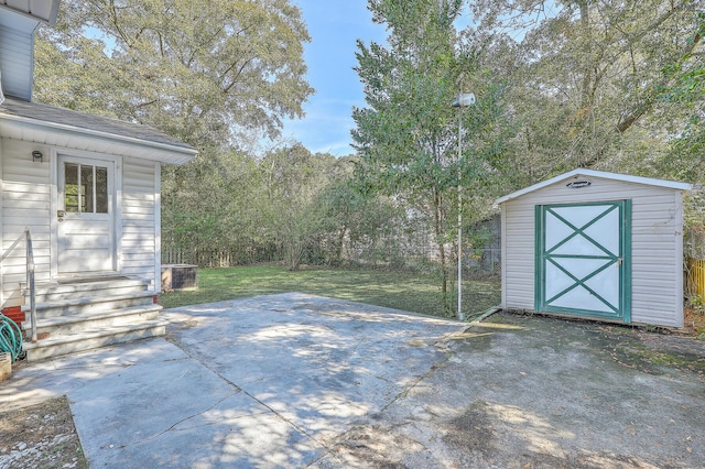 view of patio / terrace with entry steps, a storage unit, an outbuilding, and fence