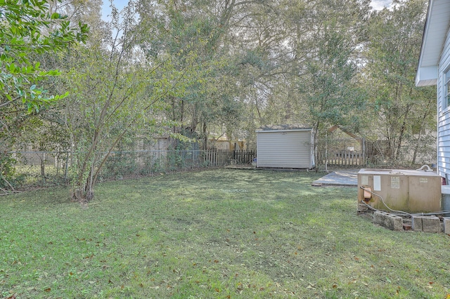 view of yard featuring a shed, a fenced backyard, and an outbuilding