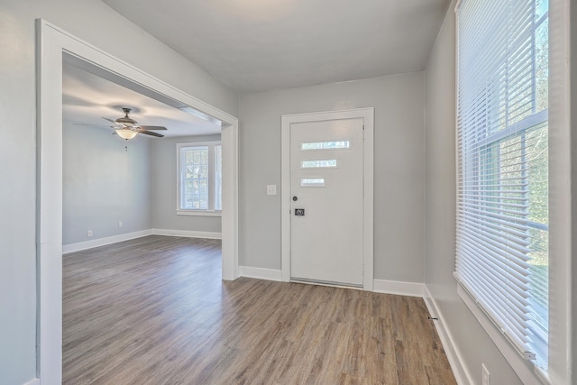 foyer entrance with a ceiling fan, baseboards, and wood finished floors