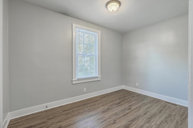 spare room featuring dark wood-style floors, visible vents, and baseboards