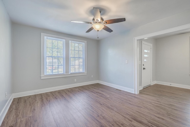 empty room featuring baseboards, visible vents, and wood finished floors