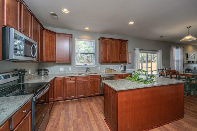 kitchen featuring a center island, decorative light fixtures, wood-type flooring, stainless steel appliances, and sink