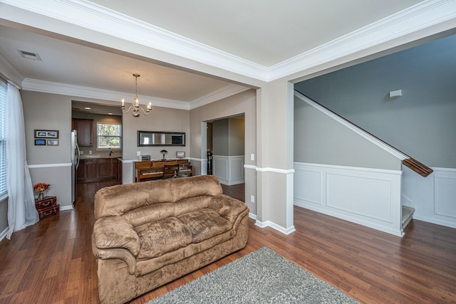 living room with dark hardwood / wood-style flooring, ornamental molding, and a notable chandelier