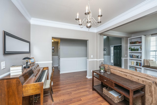 dining room with built in shelves, wood-type flooring, an inviting chandelier, and ornamental molding