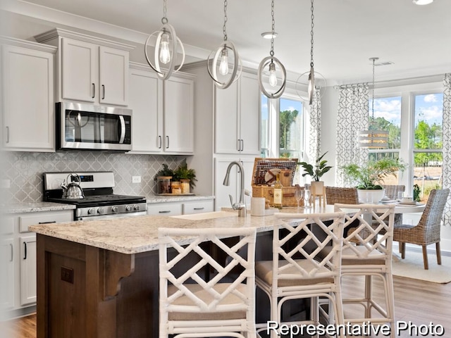 kitchen featuring tasteful backsplash, white cabinets, appliances with stainless steel finishes, and pendant lighting