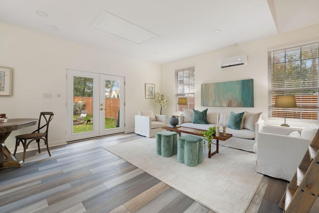 living room with light hardwood / wood-style floors, a wall unit AC, and french doors