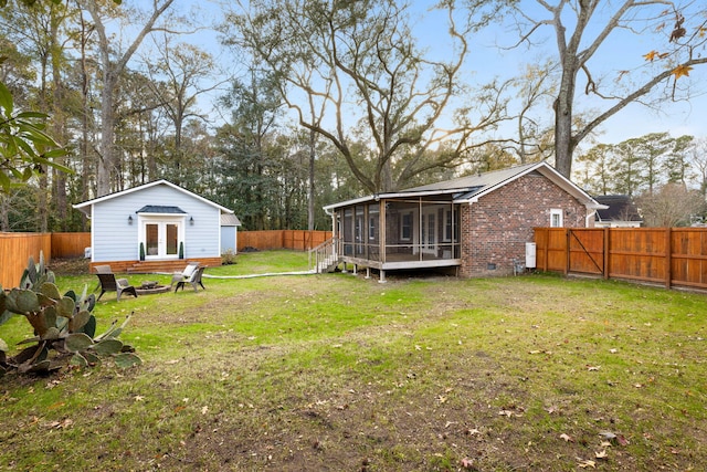 view of yard featuring a fire pit, a sunroom, and french doors