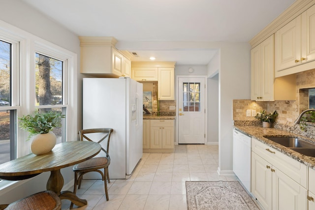 kitchen with sink, white appliances, light stone counters, and backsplash