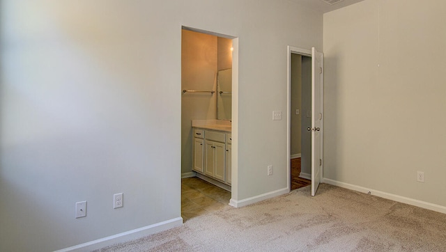 unfurnished bedroom featuring light carpet and ensuite bath