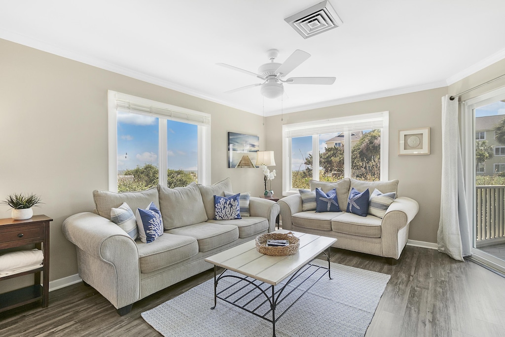 living room featuring dark hardwood / wood-style flooring, ceiling fan, crown molding, and a healthy amount of sunlight