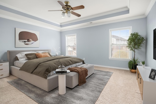 bedroom with light carpet, baseboards, a ceiling fan, ornamental molding, and a tray ceiling