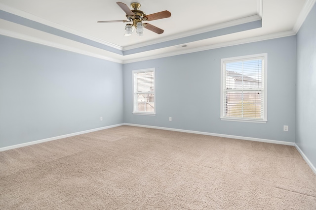 carpeted spare room featuring crown molding, a raised ceiling, ceiling fan, and baseboards