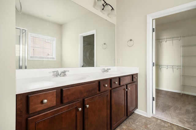 bathroom with a sink, a spacious closet, and double vanity