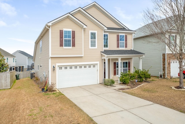 traditional home featuring a garage, concrete driveway, a front yard, and fence