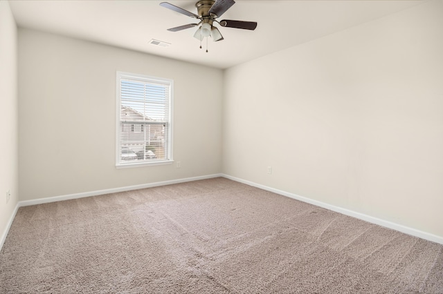 carpeted spare room with a ceiling fan, visible vents, and baseboards