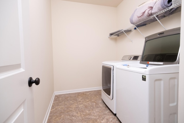 washroom with laundry area, washing machine and dryer, and baseboards