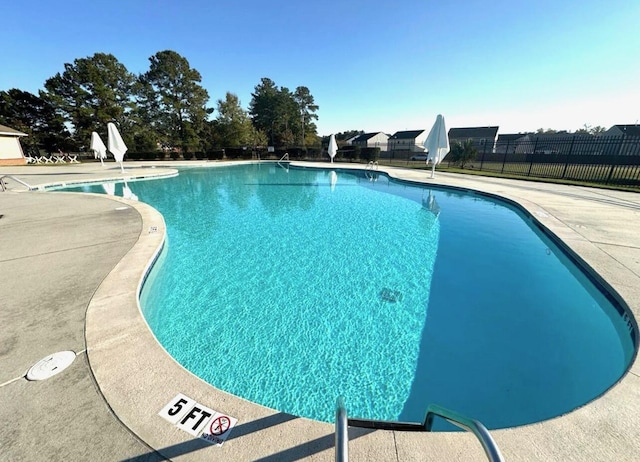 pool with a patio area and fence