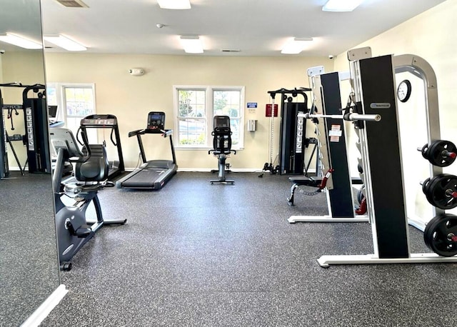 exercise room featuring arched walkways, visible vents, and baseboards