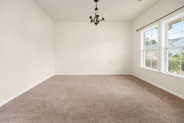 carpeted spare room with baseboards and a chandelier