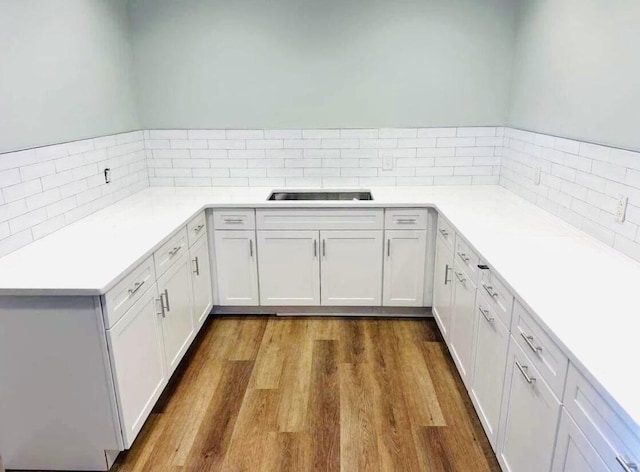 kitchen featuring light countertops, backsplash, dark wood finished floors, and white cabinets