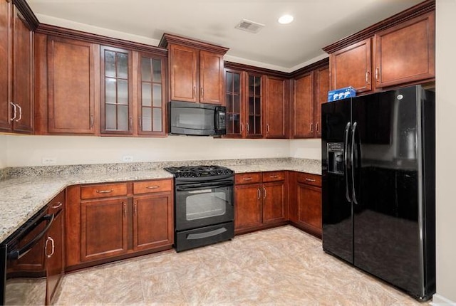 kitchen with black appliances, glass insert cabinets, visible vents, and light stone countertops