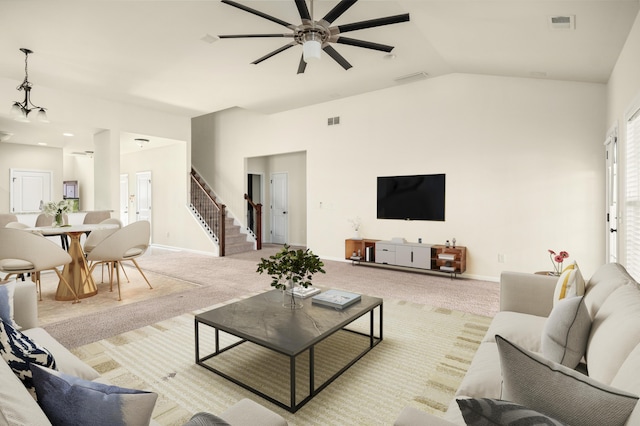 living area featuring carpet flooring, vaulted ceiling, visible vents, and stairs