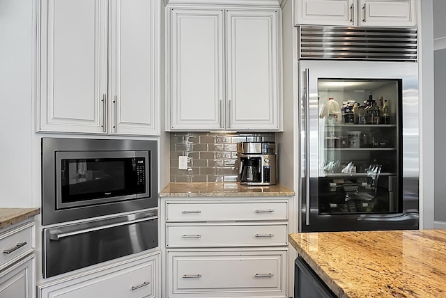 kitchen featuring light stone countertops, tasteful backsplash, wine cooler, built in appliances, and white cabinets