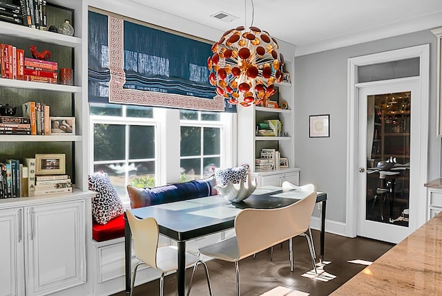 dining room with built in shelves, dark hardwood / wood-style floors, an inviting chandelier, and ornamental molding