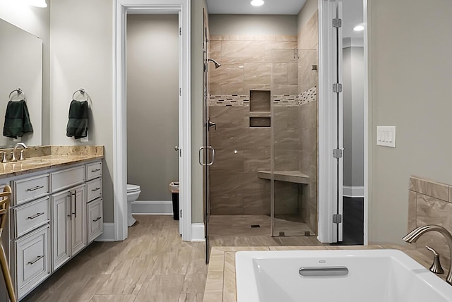 full bathroom featuring shower with separate bathtub, vanity, and toilet