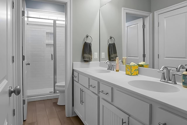 bathroom featuring vanity, hardwood / wood-style flooring, toilet, and an enclosed shower