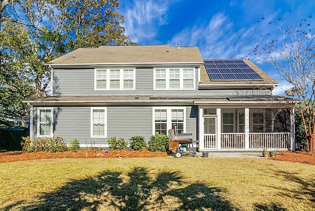 back of house featuring a sunroom, solar panels, and a yard