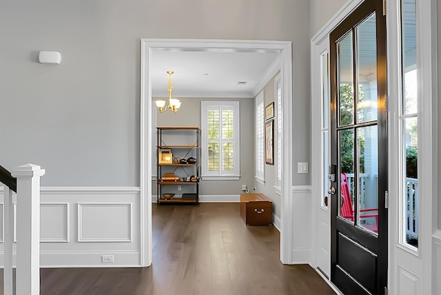 entryway featuring dark wood-type flooring, an inviting chandelier, and ornamental molding