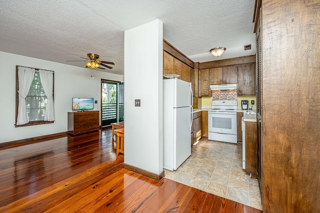 kitchen with light wood-type flooring, white appliances, ceiling fan, and tasteful backsplash